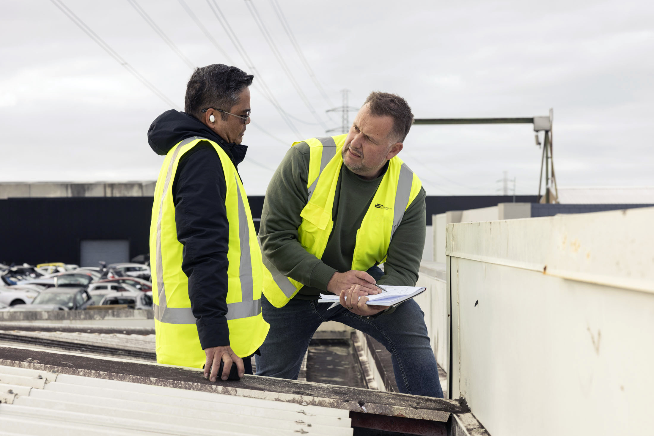 two roofers discussing requirments on a roof top in christchurch